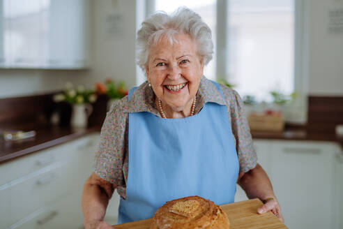 Portrait of senior woman with a fresh baked bread. - HPIF32885
