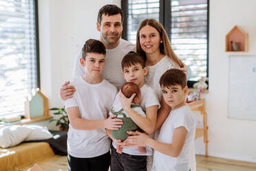Porträt einer großen Familie mit vier Söhnen, die ihr neugeborenes Baby genießen. - HPIF33015
