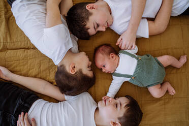 Drei große Brüder mit ihrem neugeborenen Bruder, der in einem Bett liegt. - HPIF33036