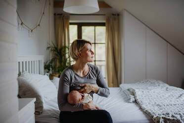 Eine Mutter, die ihr kleines Baby in ihrem Schlafzimmer stillt. - HPIF33054