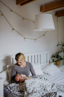 Eine Mutter, die ihr kleines Baby in ihrem Schlafzimmer stillt. - HPIF33055