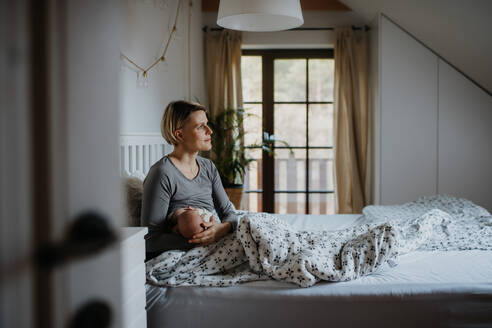 Eine Mutter, die ihr kleines Baby in ihrem Schlafzimmer stillt. - HPIF33056