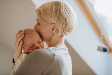 Eine Mutter, die ihr kleines neugeborenes Baby in ihrem Haus kuschelt. - HPIF33060