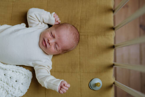 Draufsicht auf ein schlafendes neugeborenes Baby in einem kleinen Bett. - HPIF33073