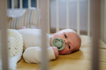 Seitenansicht eines schlafenden Neugeborenen im Bettchen. - HPIF33076