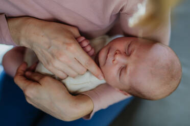 Eine Mutter, die ihr neugeborenes Baby in den Armen kuschelt. - HPIF33099