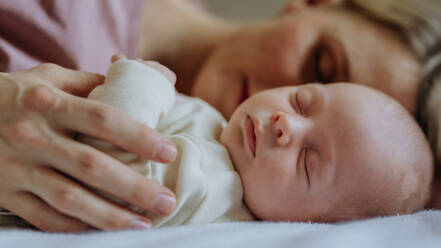 Mutter kuschelt mit ihrem neugeborenen Baby im Bett. - HPIF33132