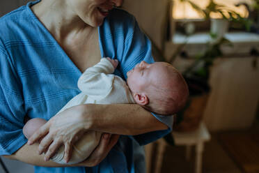 Eine Mutter, die ihr kleines neugeborenes Baby in ihrem Haus kuschelt. - HPIF33152