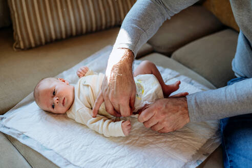 Mature father changing diaper his newborn baby. - HPIF33156