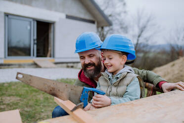 Father and his little son working together in front of their unfinished house. - HPIF33215