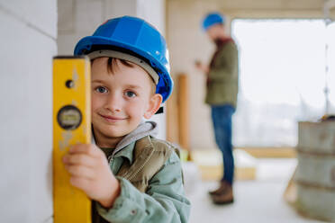 Little boy in unfinished house measuring wall in unfinished house with a spirit level. - HPIF33238