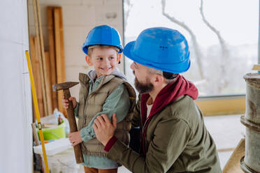 Father and his little son working together on their unfinished house. - HPIF33248