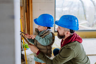 Father and his little son working together on their unfinished house. - HPIF33250