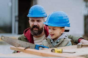 Father and his little son working together in front of their unfinished house. - HPIF33264