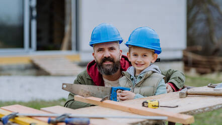 Father and his little son working together in front of their unfinished house. - HPIF33265