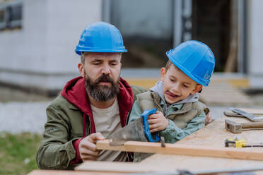 Father and his little son working together in front of their unfinished house. - HPIF33266