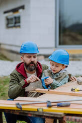 Father and his little son working together in front of their unfinished house. - HPIF33267