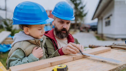 Father and his little son working together in front of their unfinished house. - HPIF33268