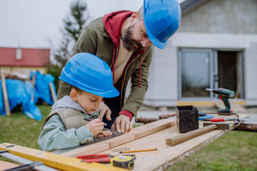 Father and his little son working together in front of their unfinished house. - HPIF33270