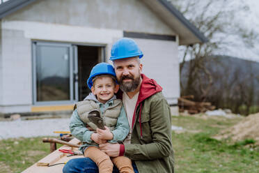 Portrait of father with his little son in front of their new unfinished house. - HPIF33275