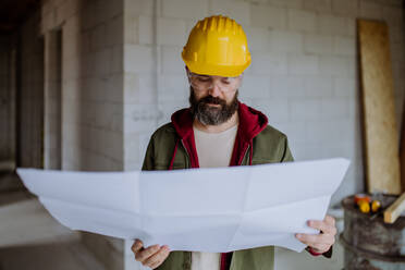 Portrait of mature man working in his new unfinished house. - HPIF33287