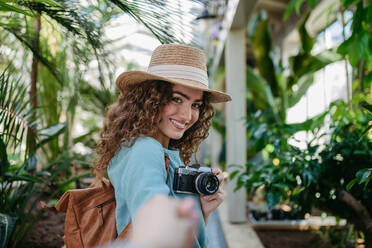 Porträt einer jungen schönen Frau mit Kamera im botanischen Garten. - HPIF33313