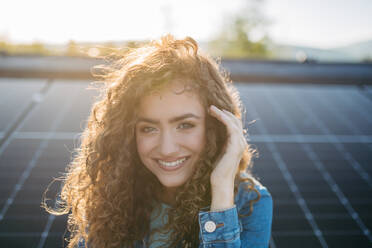 Portrait of young woman, owner on roof with solar panels. - HPIF33339