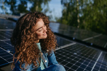 Portrait of young woman, owner on roof with solar panels. - HPIF33342