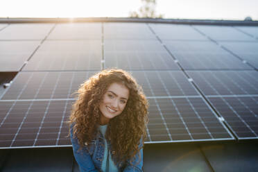 Portrait of young woman, owner on roof with solar panels. - HPIF33357