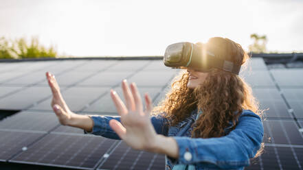 Young woman with virtual goggles on a roof with solar panels. - HPIF33363