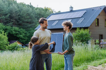 Father and his children standing in front of their house with photovoltaics on the roof. - HPIF33366