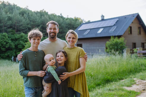 Happy family near their house with a solar panels. Alternative energy, saving resources and sustainable lifestyle concept. - HPIF33368