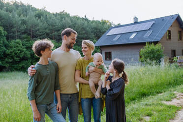 Happy family near their house with a solar panels. Alternative energy, saving resources and sustainable lifestyle concept. - HPIF33369