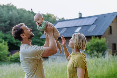 Happy family near their house with a solar panels. Alternative energy, saving resources and sustainable lifestyle concept. - HPIF33374