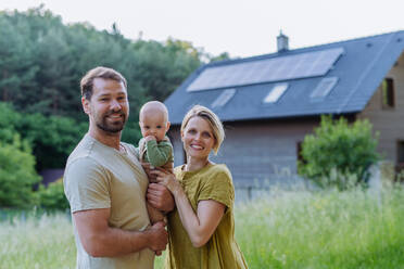 Happy family near their house with a solar panels. Alternative energy, saving resources and sustainable lifestyle concept. - HPIF33375