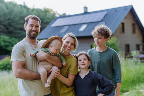 Happy family near their house with a solar panels. Alternative energy, saving resources and sustainable lifestyle concept. - HPIF33377