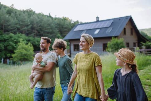 Happy family near their house with a solar panels. Alternative energy, saving resources and sustainable lifestyle concept. - HPIF33378