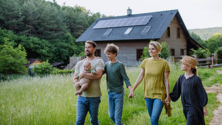 Happy family near their house with a solar panels. Alternative energy, saving resources and sustainable lifestyle concept. - HPIF33379