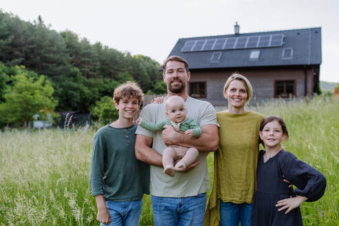 Happy family near their house with a solar panels. Alternative energy, saving resources and sustainable lifestyle concept. - HPIF33389