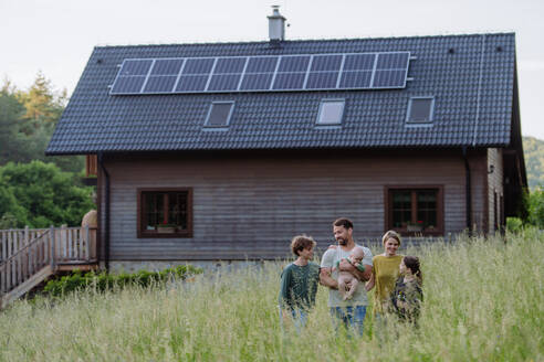 Happy family near their house with a solar panels. Alternative energy, saving resources and sustainable lifestyle concept. - HPIF33394