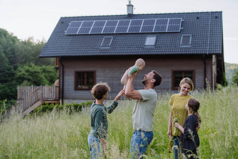 Happy family near their house with a solar panels. Alternative energy, saving resources and sustainable lifestyle concept. - HPIF33395