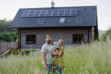 Happy family near their house with a solar panels. Alternative energy, saving resources and sustainable lifestyle concept. - HPIF33396