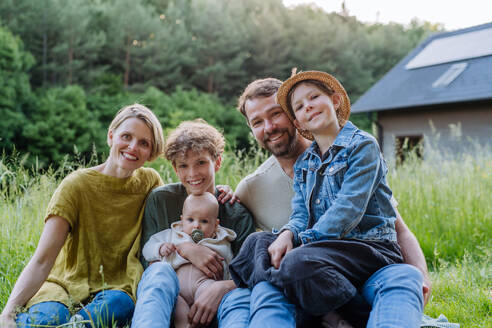 Happy family near their house with a solar panels. Alternative energy, saving resources and sustainable lifestyle concept. - HPIF33406