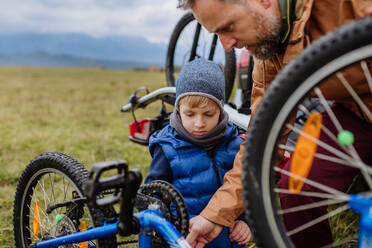 Kleiner Junge, der seinem Vater hilft, ein Fahrrad auf dem Gepäckträger zu befestigen. Vorbereitung für eine Fahrradtour in der Natur, Abstellen von Fahrrädern von Autoträgern. Konzept der gesunden Lebensweise und der Bewegung. - HPIF33480