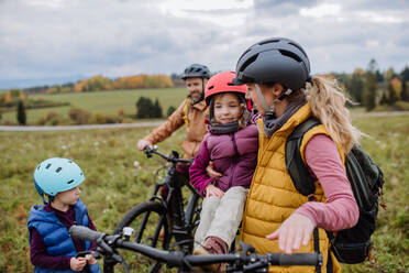 Junge Familie mit kleinen Kindern, die sich auf eine Fahrradtour in der Natur vorbereiten. Konzept der gesunden Lebensweise und der bewegten Aktivität. - HPIF33484