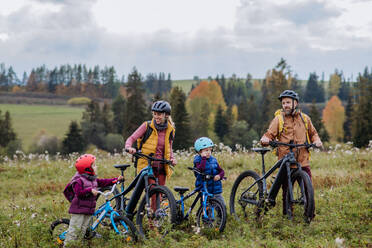 Junge Familie mit kleinen Kindern auf Fahrrädern, inmitten der herbstlichen Natur, Konzept der gesunden Lebensweise. - HPIF33488