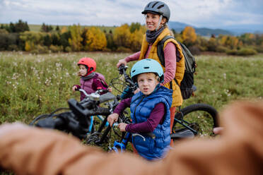 Junge Familie mit kleinen Kindern, die sich auf eine Fahrradtour in der Natur vorbereiten. Konzept der gesunden Lebensweise und der bewegten Aktivität. - HPIF33490