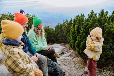 Kleines Mädchen, das Fotos von ihrer Familie macht, während sie eine Pause beim Wandern in den Bergen macht. - HPIF33516