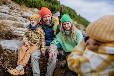 Little girl taking pictures of her family during a hike. Happy family hiking together in an autumn mountains. - HPIF33517