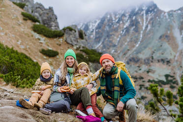 Glückliche Familie, die sich ausruht und bei einer Wanderung in den herbstlichen Bergen eine Kleinigkeit isst. - HPIF33533